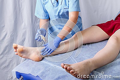 Doctor cosmetician makes the procedure shugaring sugar paste on the right ankle to a young woman Stock Photo