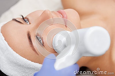 The doctor-cosmetologist makes the apparatus a procedure of Hardware face cleaning with a soft rotating brush Stock Photo