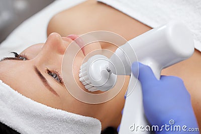 The doctor-cosmetologist makes the apparatus a procedure of Hardware face cleaning with a soft rotating brush Stock Photo