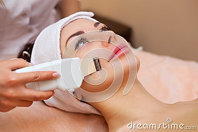 The doctor-cosmetologist makes the apparatus a procedure of ultrasound cleaning of the facial skin Stock Photo