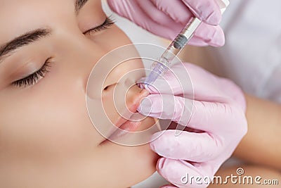 The doctor cosmetologist makes Lip augmentation procedure of a beautiful woman Stock Photo