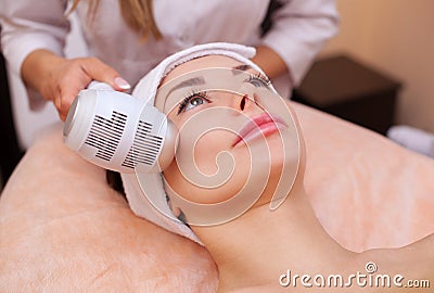 The doctor-cosmetologist makes the procedure Cryotherapy of the facial skin of a beautiful, young woman in a beauty salon Stock Photo