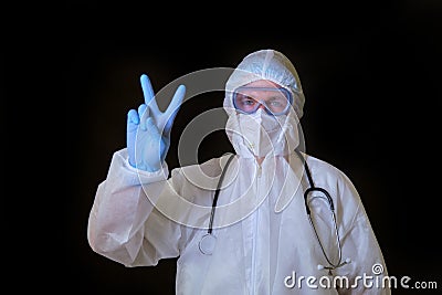 A doctor in a covid protective suit shows a victory gesture with two fingers Stock Photo