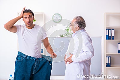 Doctor dietician and happy patient wearing large trousers Stock Photo
