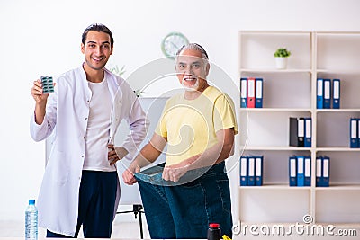 Doctor dietician and happy patient wearing large trousers Stock Photo