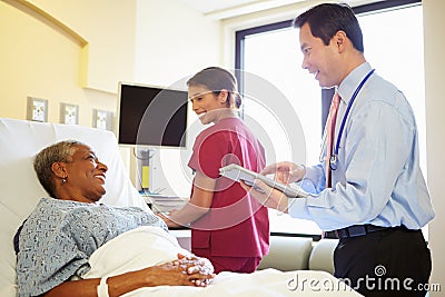 Doctor With Digital Tablet Talks To Woman In Hospital Bed Stock Photo