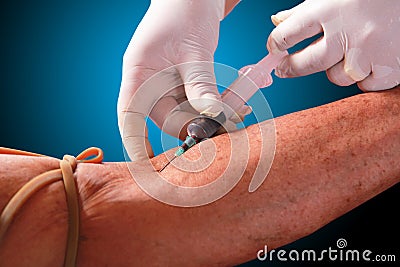 Doctor drawing blood sample from arm for blood test on blue back Stock Photo