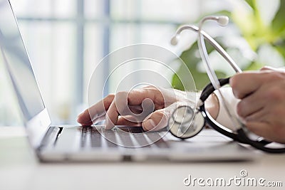 Doctor entering patient notes on laptop in surgery Stock Photo