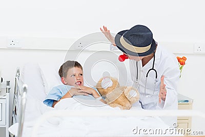 Doctor entertaining sick boy in hospital bed Stock Photo