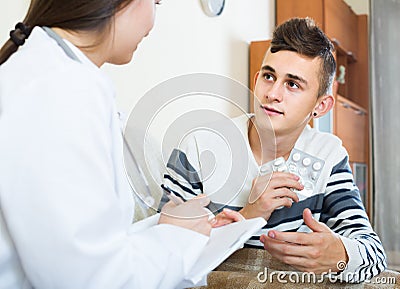 Doctor examinating teen boy with quinsy at home Stock Photo