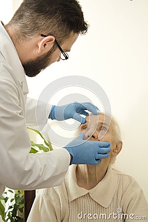 Doctor examines the eyes, conjunctival very old woman The doctor geriatrician during the test. Stock Photo