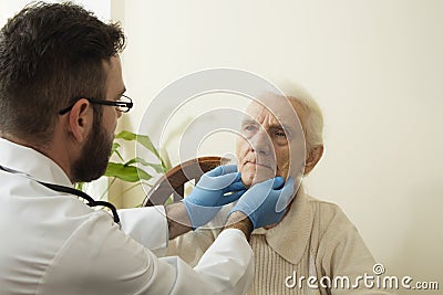 Doctor examines the lymph nodes on the neck of an old woman. Stock Photo