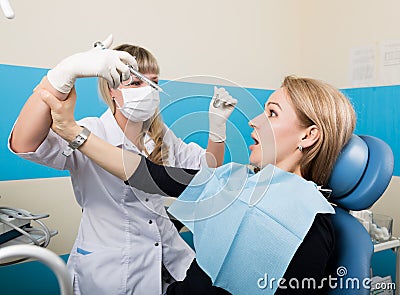 Doctor examines the oral cavity on tooth decay. Caries protection. Tooth decay treatment. Doctor puts injection to the Stock Photo