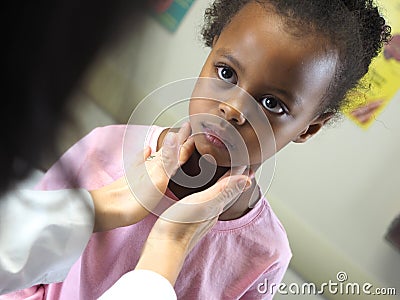 Doctor examining an African-American child`s throat in a hospital Stock Photo