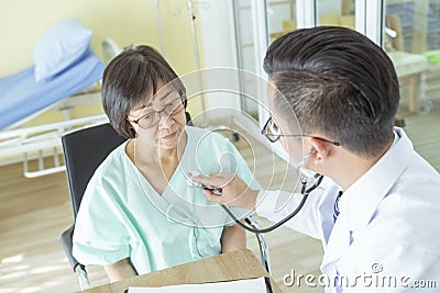 Doctor is examining Elderly woman patient using a stethoscope. Stock Photo