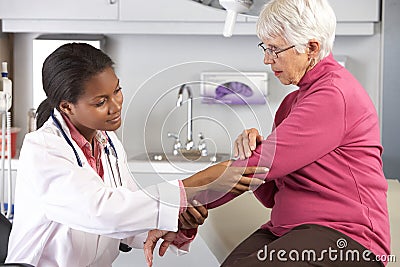 Doctor Examining Female Patient With Elbow Pain Stock Photo