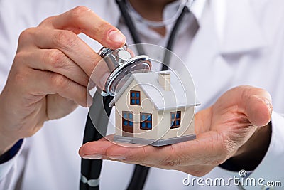 Doctor Examining House Model With Stethoscope Stock Photo