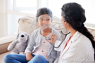 Doctor examining a little girl with stethoscope. Female paediatrician listening to childs heartbeat during home visit or Stock Photo