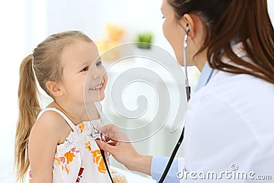 Doctor examining a little girl by stethoscope. Happy smiling child patient at usual medical inspection. Medicine and Stock Photo