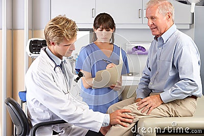 Doctor Examining Male Patient With Knee Pain Stock Photo