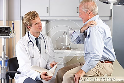 Doctor Examining Male Patient With Shoulder Pain Stock Photo