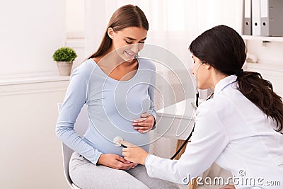 Doctor Examining Pregnant Woman Holding Stethoscope Near Belly In Office Stock Photo