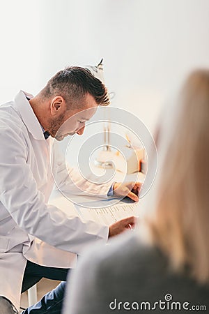 Doctor filling a blank form with a patient. Stock Photo