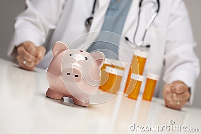Doctor Fists on Table Behind Bottle and Piggy Bank Stock Photo