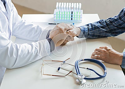 Doctor giving encouragement to elderly patient by holding his hands Stock Photo