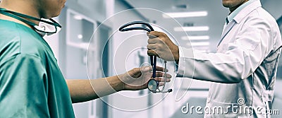 Doctor giving stethoscope to surgeon Referral Stock Photo