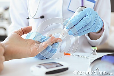 Doctor with gloves piercing patients finger with lancet closeup Stock Photo