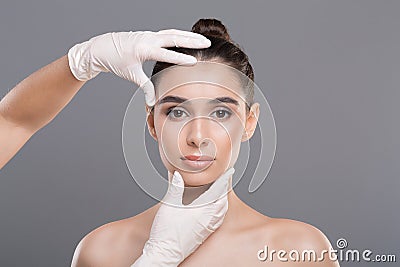 Doctor in gloves touch woman face, gray background Stock Photo