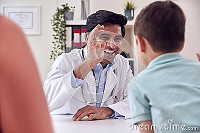 Doctor Or GP In White Coat Meeting Mother And Son For Appointment Giving Boy High Five Stock Photo