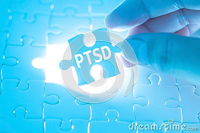 Doctor hand holding a jigsaw puzzle with PTSD - post traumatic s Stock Photo