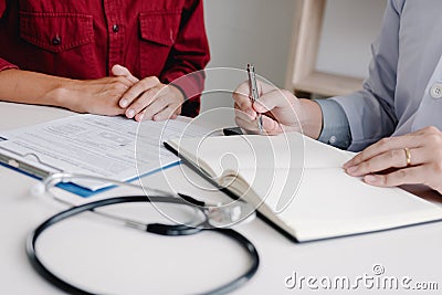 Doctor hand holding pen writing patient history list on note pad and talking to the patient about medication and treatment Stock Photo