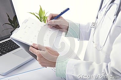 Doctor hand marked appointment for patient on calendar. Stock Photo