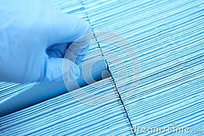 Doctor hand in rubber gloves pulling out sterile disposable napkin from packaging closeup Stock Photo
