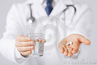 Doctor hands giving white pills and glass of water Stock Photo