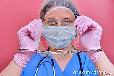 Doctor hands in handcuffs on pink background, close up. Young woman hands in medical gloves handcuffed, coronavirus quarantine Stock Photo