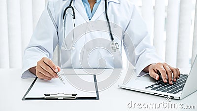 Doctor hold pen to record patient data on clipboard and computer Stock Photo