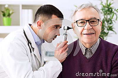 Doctor holding otoscope and examining patient ear Stock Photo