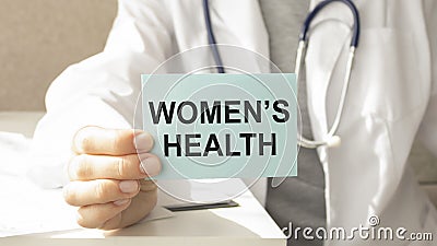 Doctor holding paper with text WOMEN`S CARE Stock Photo