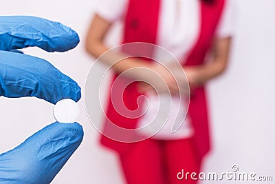 Doctor is holding a pill in her hand against the background of a girl who has abdominal pain and bloating, medicine Stock Photo