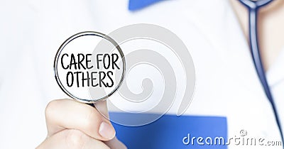 Doctor holding a stethoscope with text CARE FOR OTHERS medical concept Stock Photo