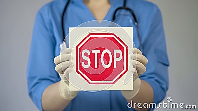 Doctor holding stop sign, warning about unhealthy lifestyle, harmful habits Stock Photo