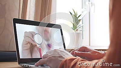 Unknown doctor holds stethoscope bell on the screen of a laptop at home. Modern telemedicine related shot Stock Photo