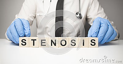 Doctor holds wooden cubes in his hands with text stenosis Stock Photo