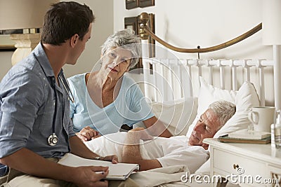 Doctor On Home Visit Discussing Health Of Senior Male Patient With Wife Stock Photo