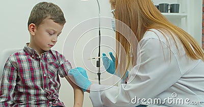 A doctor injects a vaccine into the boy shoulder. The concept of vaccination of children and the prevention of Stock Photo