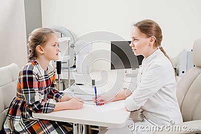 doctor interviews little girl before being examined in ophthalmologist& x27;s office. Stock Photo